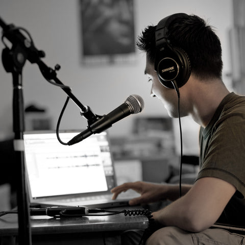 Man wearing headphones recording with a Shure SM58 microphone